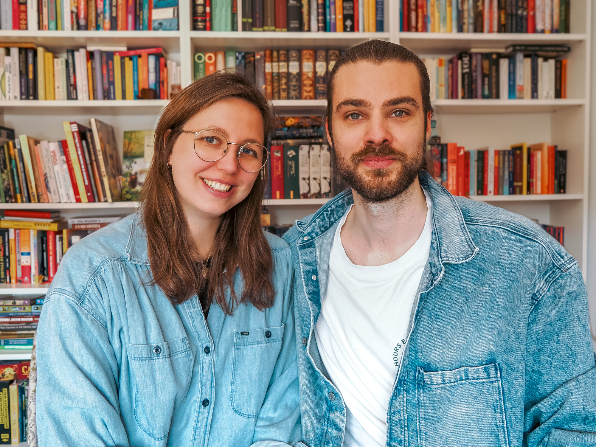 Jukes Studio Teamfoto, Rike und Julius sitzen vor Bücherregal, Website Erstellung und Online Marketing für deinen Erfolg